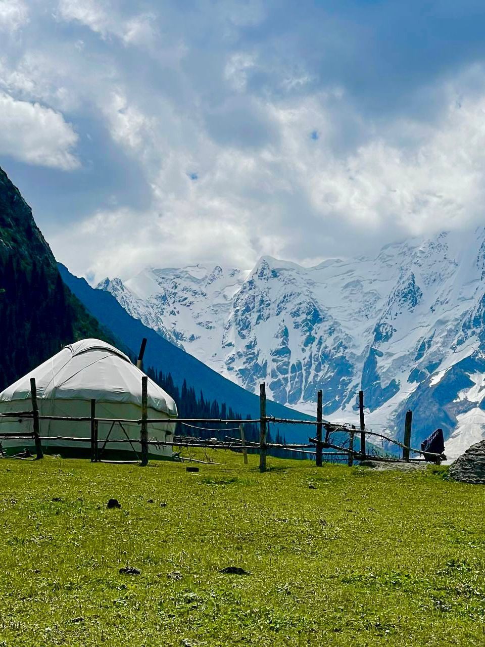 Kyrgyz yurt in a green alpine valley, mountains behind